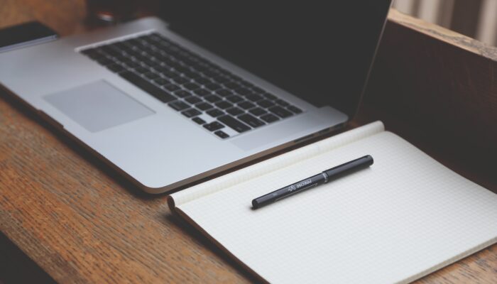 Pracovní stůl s notebookem a dokumenty symbolizující přípravu zaměstnaneckého akciového programu (ESOP) ve firmě.